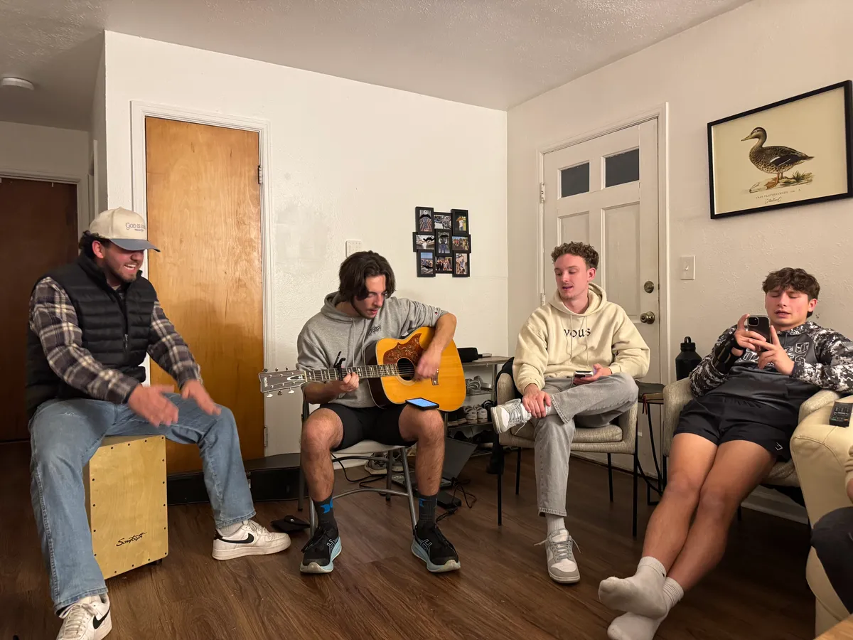 Campus Forge men hanging out and playing guitar in a living room