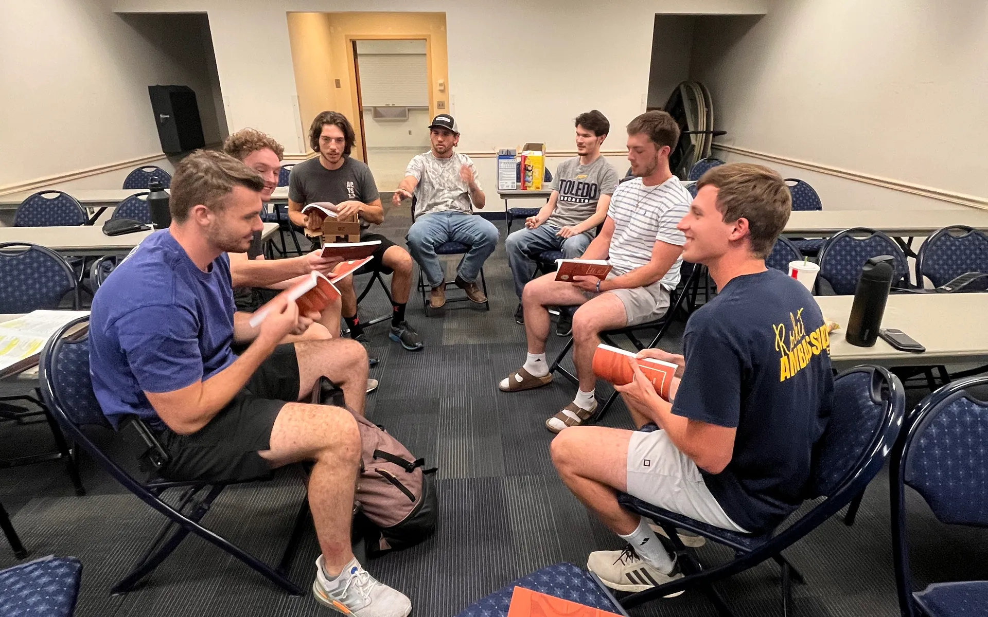 A group of Campus Forge men gathered indoors, reading together